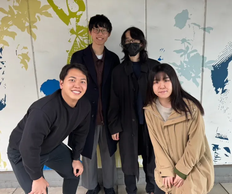 笑顔でポーズをとる若者4人の集合写真