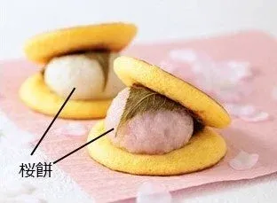 桜餅と思われるピンク色の餅と白い餅が、黄色い生地に挟まれた和菓子が2つ並んでいます