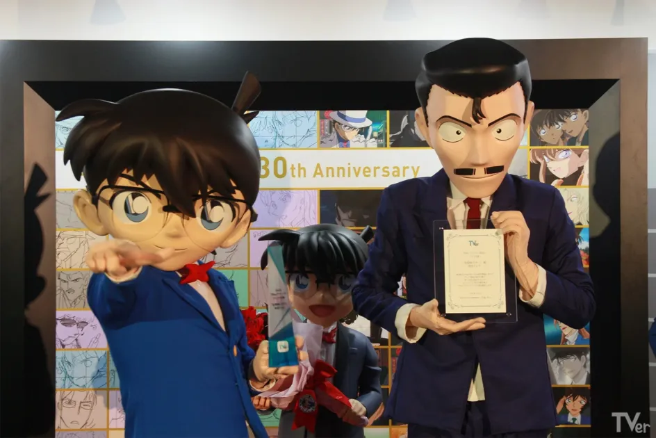 「名探偵コナン」の江戸川コナンと毛利小五郎の等身大フィギュアが並ぶイベント風景。毛利小五郎がTVerアワードを持ち、背景には「30th Anniversary」の文字。中央には小さなコナンもいる。