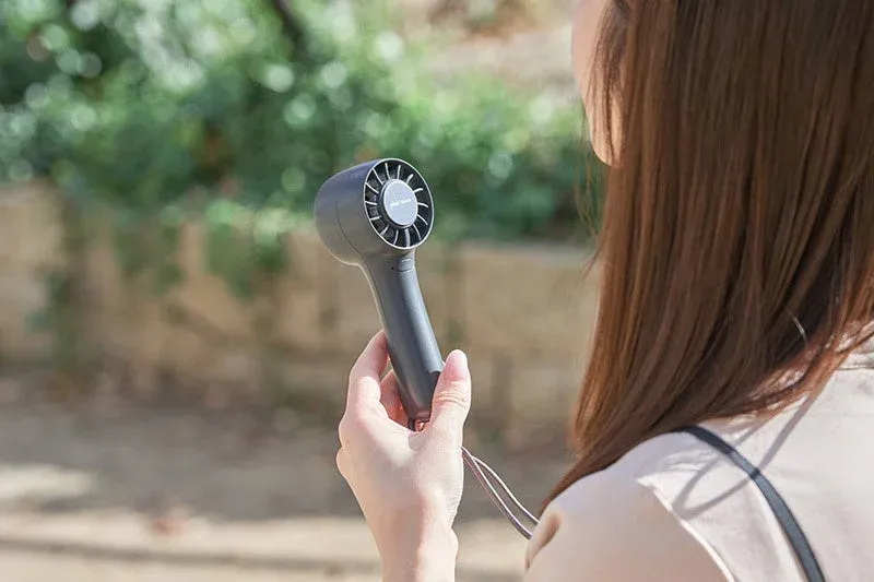 屋外でハンディファンを使用する女性