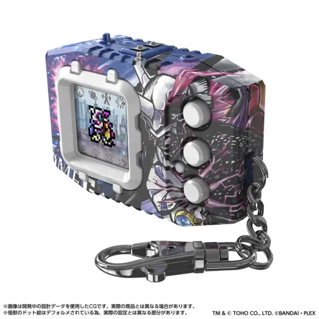 青と紫を基調とした複雑なデザインの携帯型育成ゲーム機が写っています。画面にはドット絵のキャラクターが表示され、側面には白いボタン、下部にはキーホルダーが付属しています。開発中のCG画像である旨の注意書きがあります。