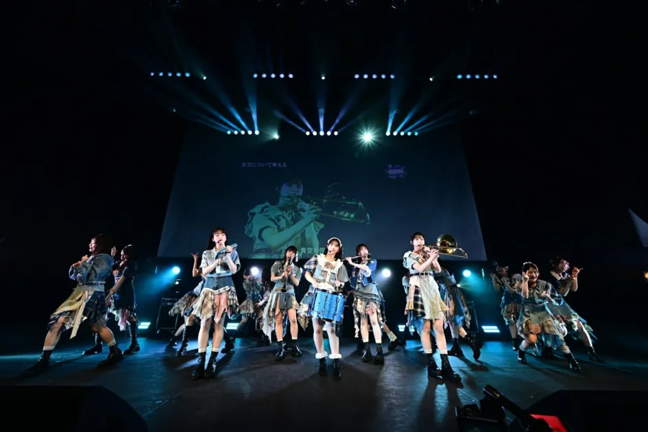アイドルグループが楽器を演奏しながらステージでパフォーマンス
