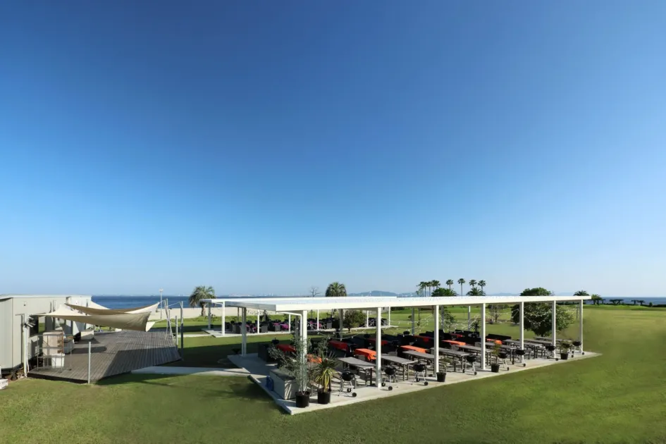 海を背景にバーベキューエリアとウッドデッキが配置された屋外施設