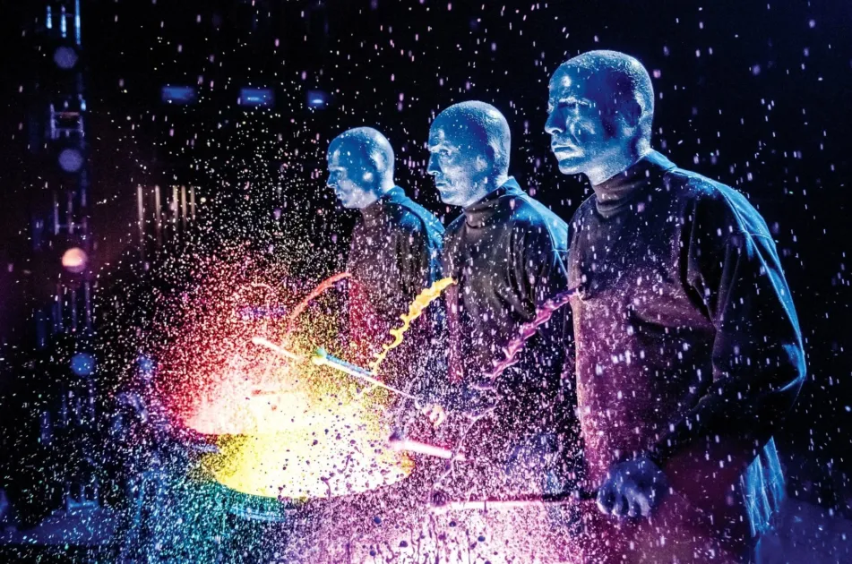 青いパフォーマーがドラムを叩き、カラフルな液体を飛び散らせるブルーマングループのパフォーマンス