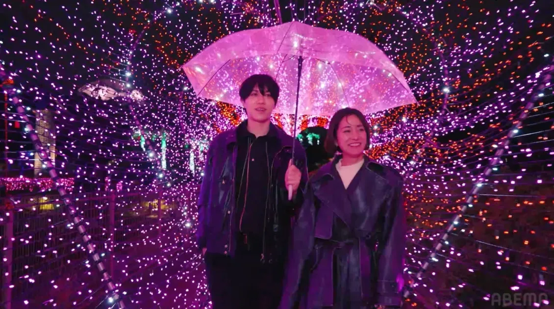 無数の紫色のイルミネーションが輝くトンネルの中を、透明な傘を差した若い男女が笑顔で歩いている