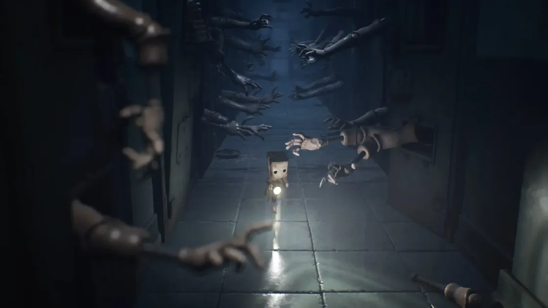 懐中電灯を持つ小さなキャラクターが、壁から伸びる無数の手に囲まれた暗く不気味な通路を進む