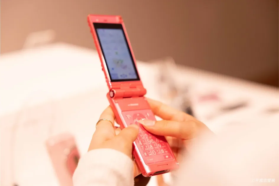 ピンクのフリップフォン(ガラケー)を操作する様子