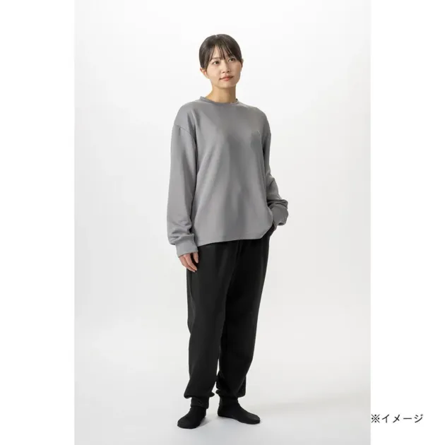 グレーの長袖トップスと黒いスウェットパンツを着用した女性