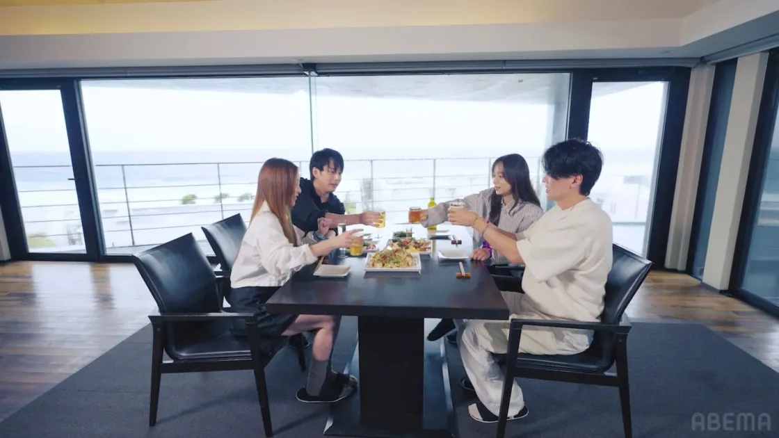 オーシャンビューの部屋で食事をしながら乾杯する男女4人のグループ