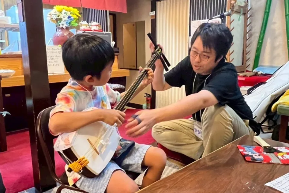 男性が子供に三味線を教えている様子