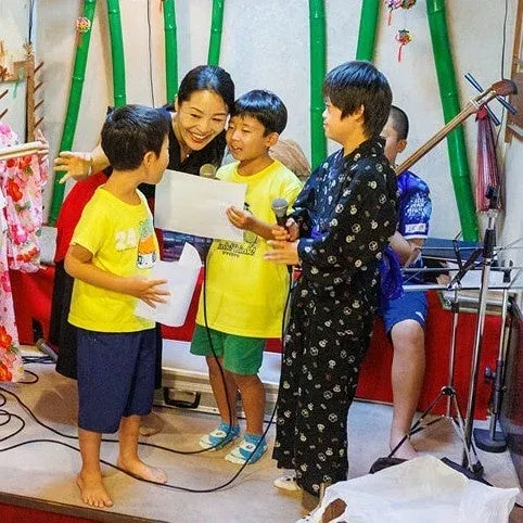子供たちと交流し、マイクを持つ女性