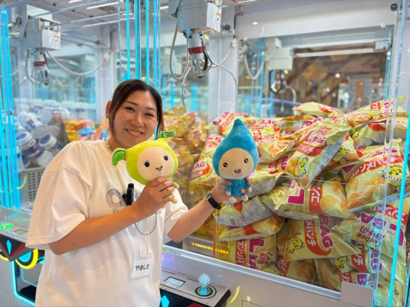 クレーンゲームの前で景品を手に笑顔の女性