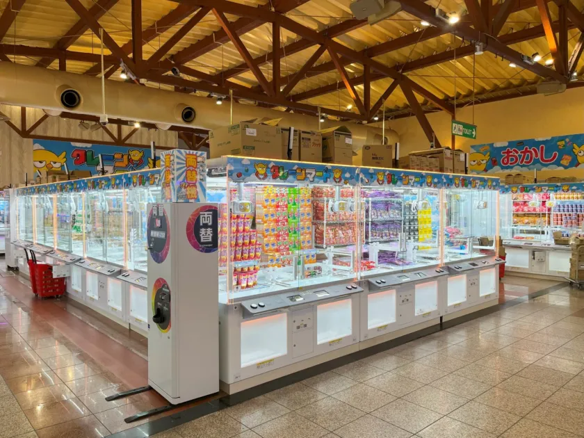 スナック菓子などが景品として並べられたクレーンゲーム機が多数設置されている店内の様子