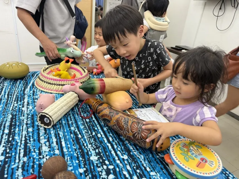 子供たちが様々な民族楽器やユニークなおもちゃに触れて遊ぶ様子