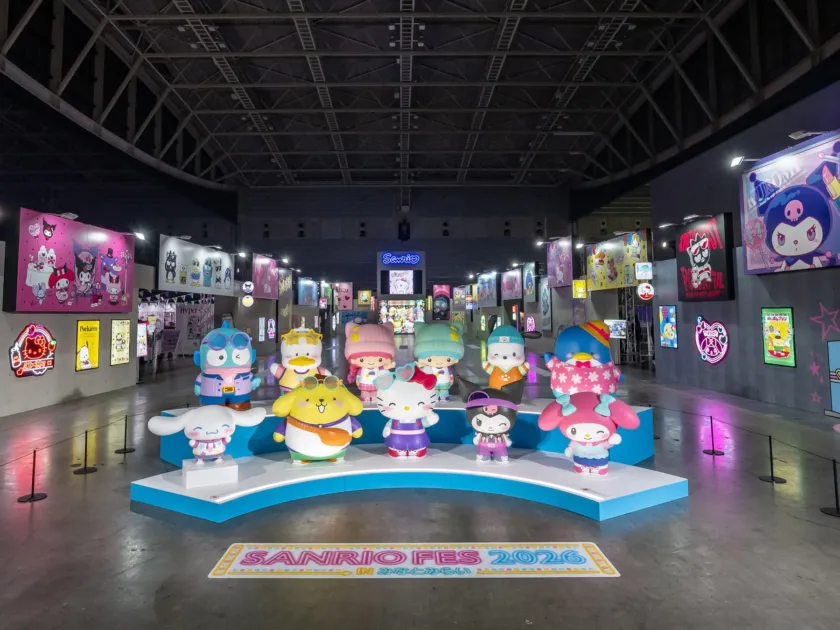 サンリオキャラクターの大型フィギュアが並ぶ「SANRIO FES 2026 in みなとみらい」の展示会場の様子。多くのキャラクターパネルやネオンサインが飾られ、賑やかな雰囲気が伝わる。
