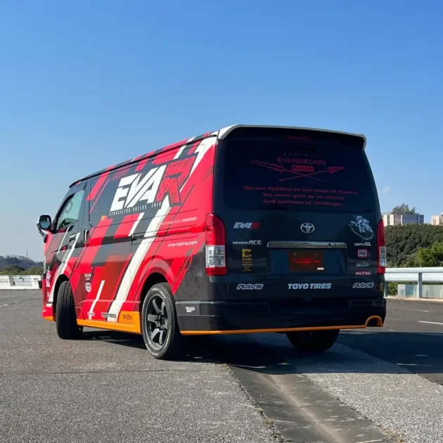 エヴァンゲリオンレーシング仕様のトヨタハイエースが青空の下、屋外の道路に停車