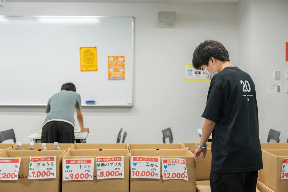 室内で男性が段ボール箱に並べられた食品を整理している様子