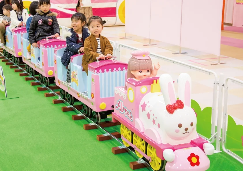 子供たちがピンクの可愛らしい列車に乗って楽しんでいる様子。先頭車両はうさぎの形をしており、メルちゃん人形が乗っている。