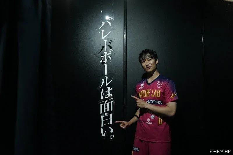 黒い背景に「バレーボールは面白い。」と書かれた文字の横で、スポーツユニフォームを着た男性が笑顔で文字を指差している