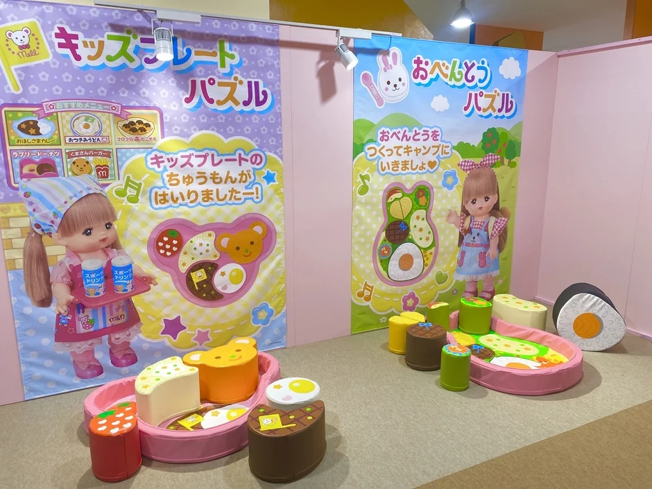 子供向けのおもちゃ展示スペースで、「キッズプレートパズル」と「おべんとうパズル」の大型ディスプレイと実物のパズルが並べられています。